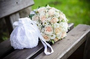 Der Brautstrauß mit hellen Rosen auf einer hölzernen Bank. 